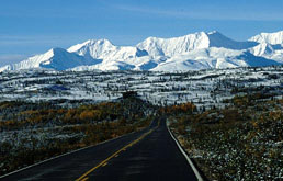 Alaska, Nordamerika, USA: Eine einsame Straße inmitten von Wildnis vor der schneebedeckten Alaska-Bergkette